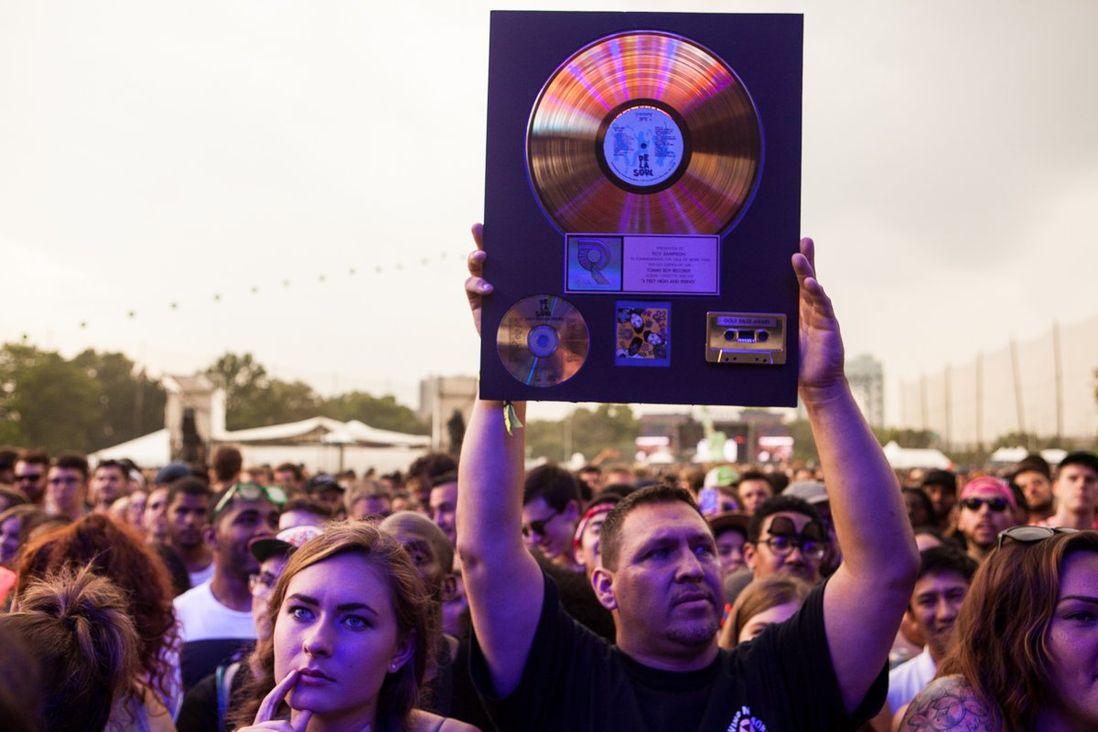 A fan holds his gold record of De La Soul's 'Three Feet High And Rising' before they take the stage.</br>